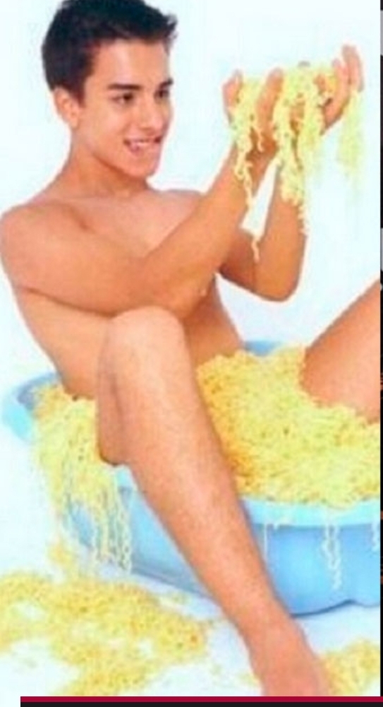 Junior, naked, on a small plastic basket filled with Miojo, a cheap brand of instant noodles